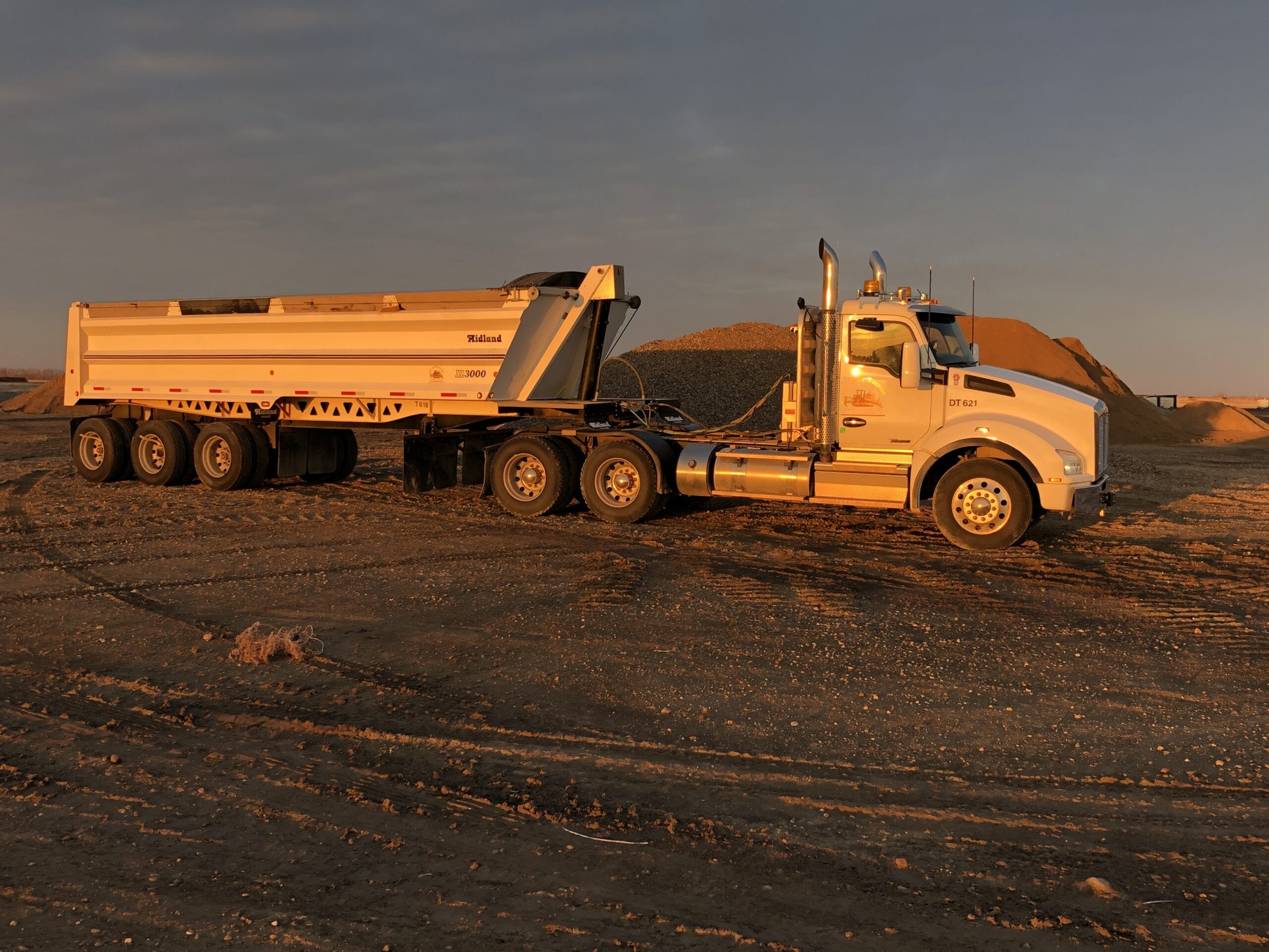 Semi-truck at dusk pulling a load of gravel to the landfill.